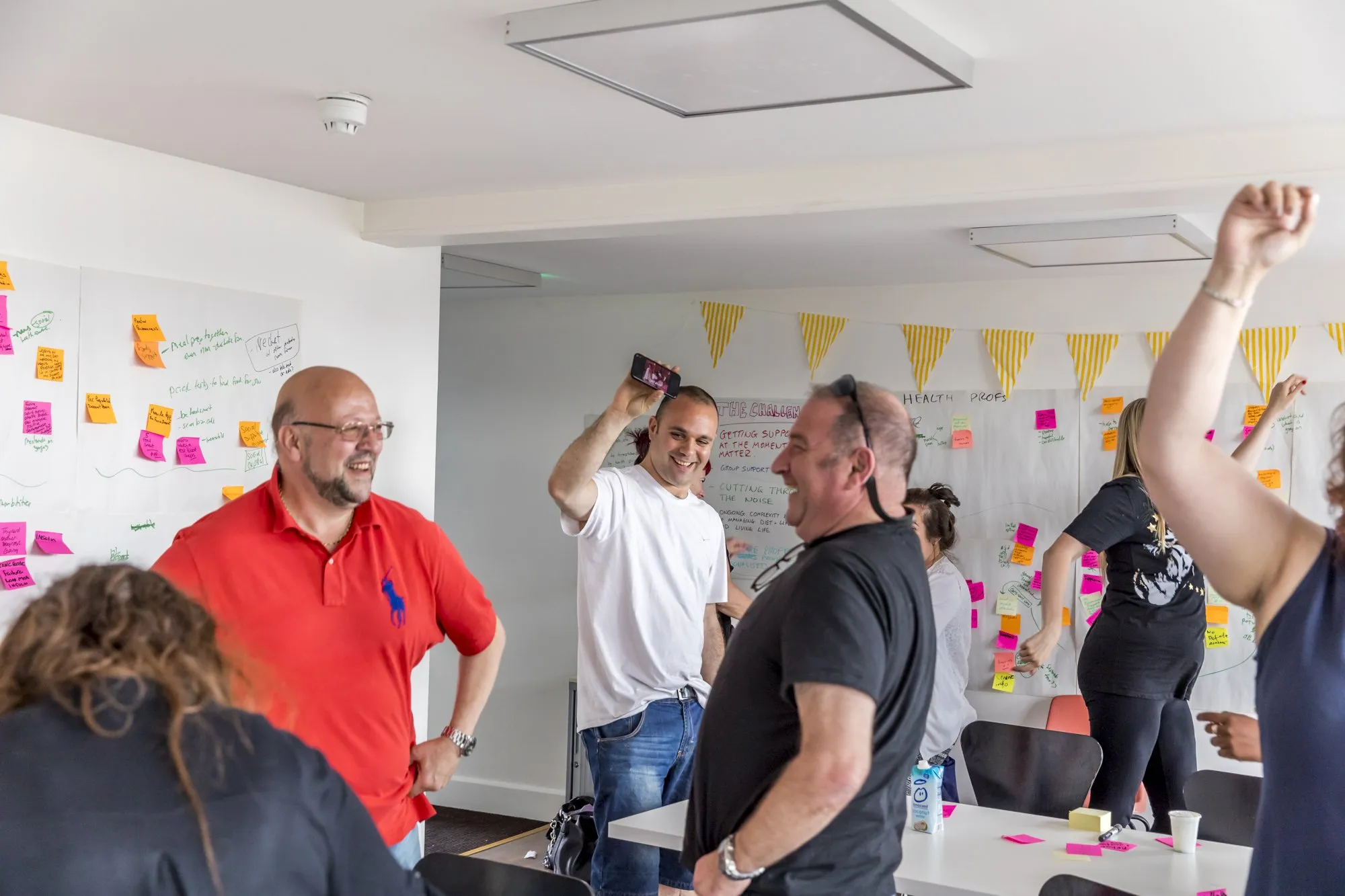 People laugh and cheer together at a workshop, one with a fist in the air