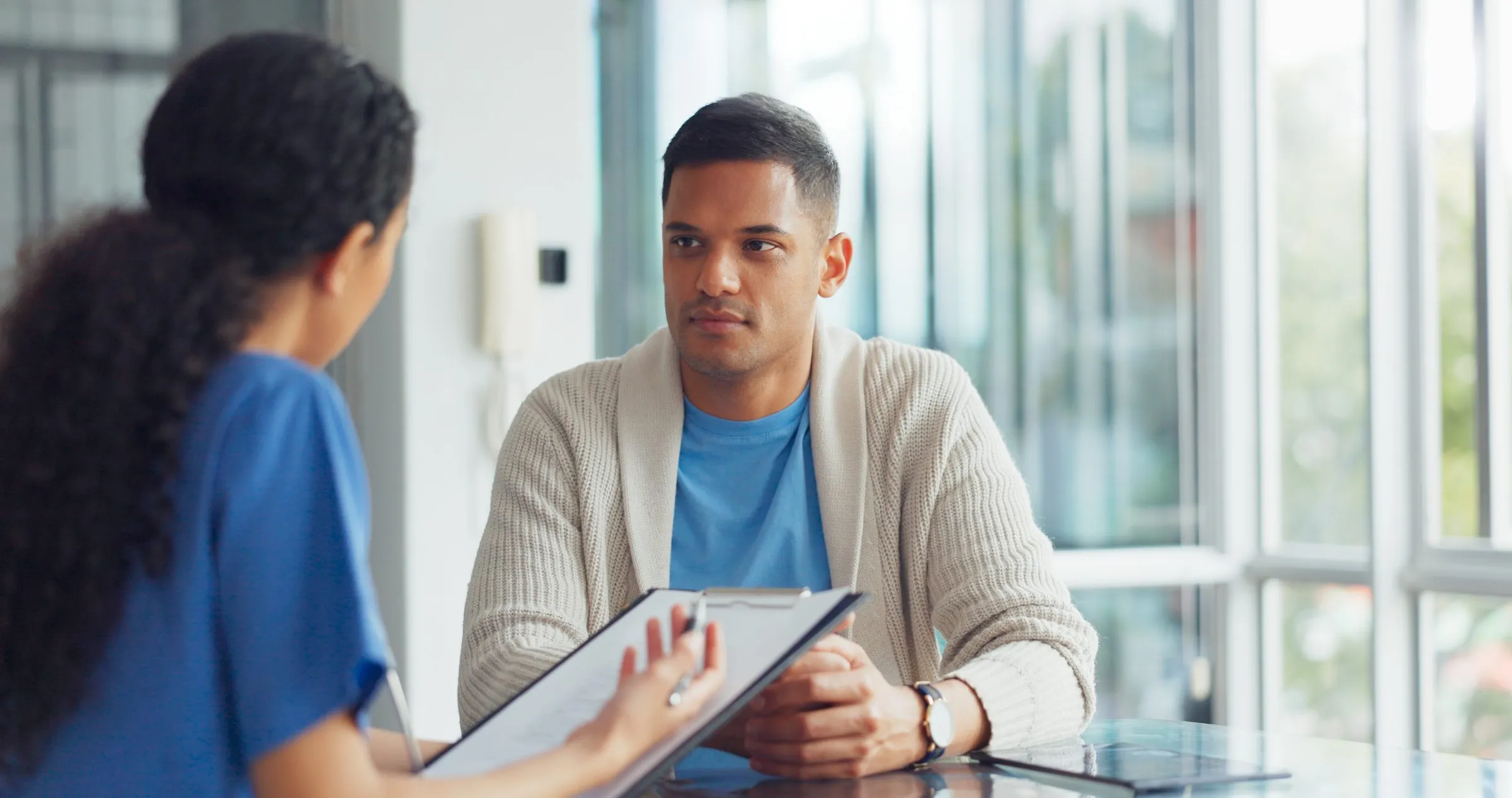 A clinician talks with a man in a consulting room