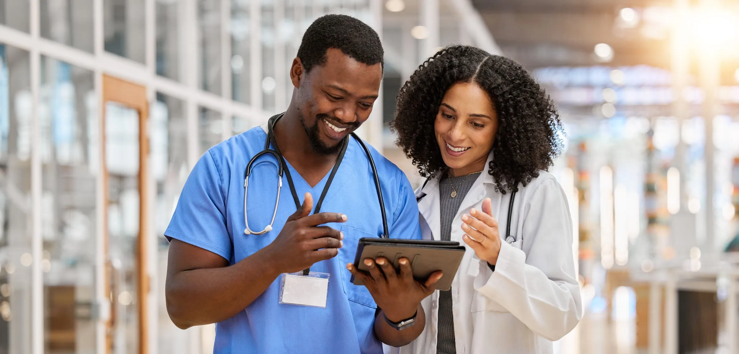 Two clinicians smile as they look at a tablet together