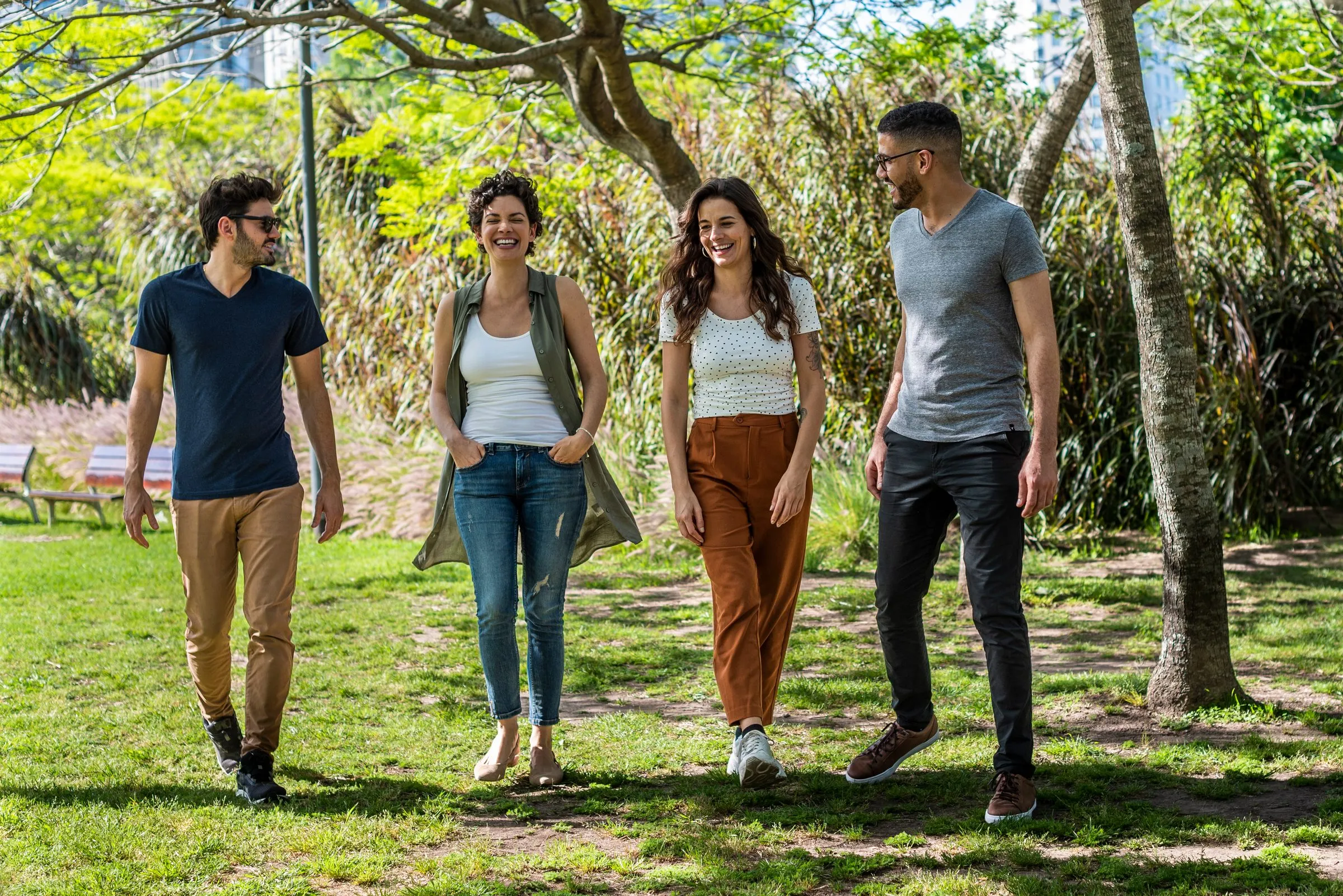 Four friends walk together through a park