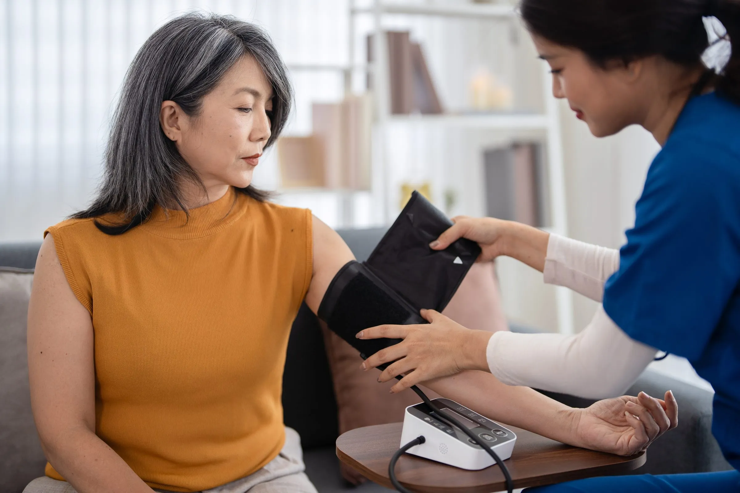 A nurse checks a woman’s blood pressure at home