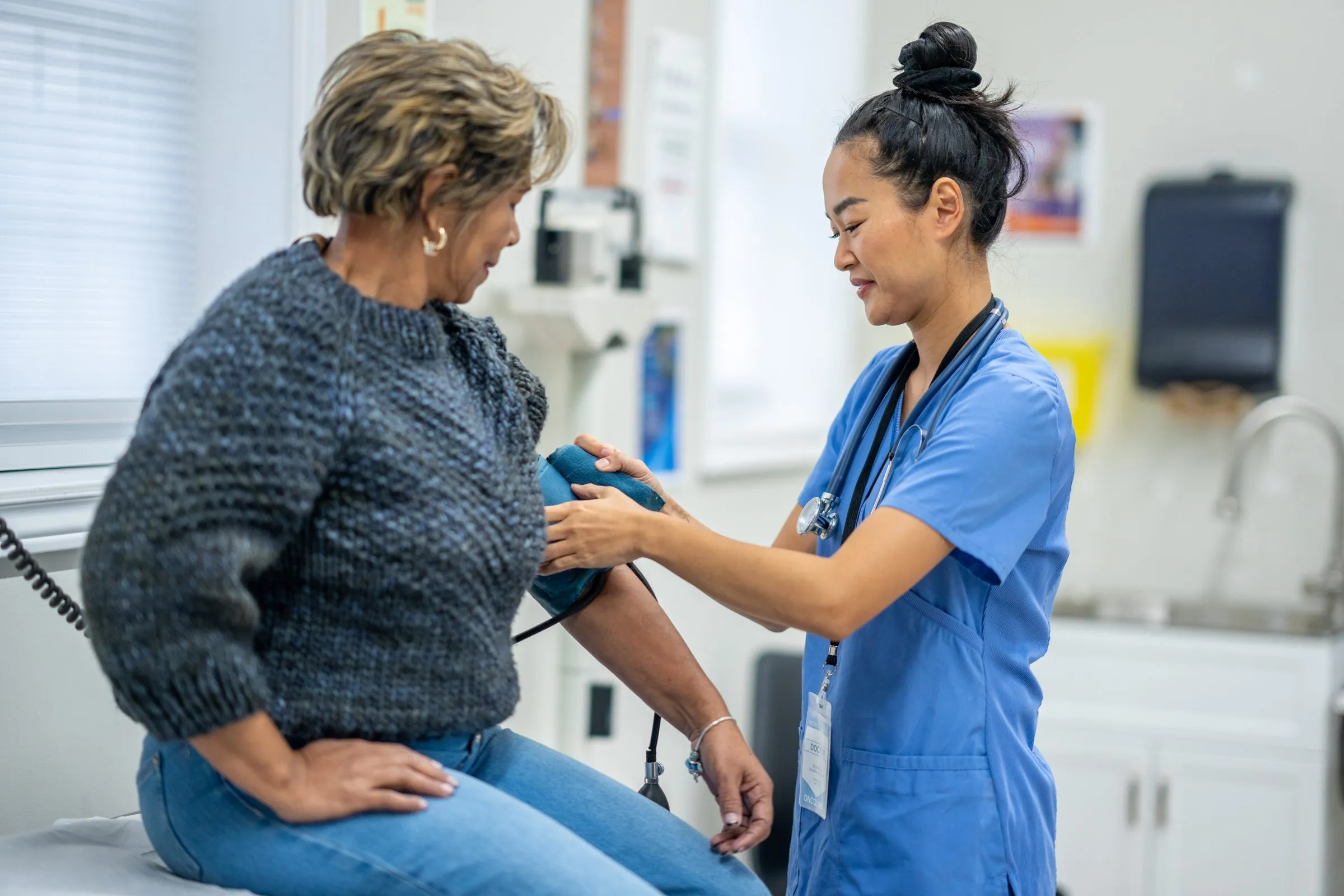 A nurse takes a woman’s blood pressure