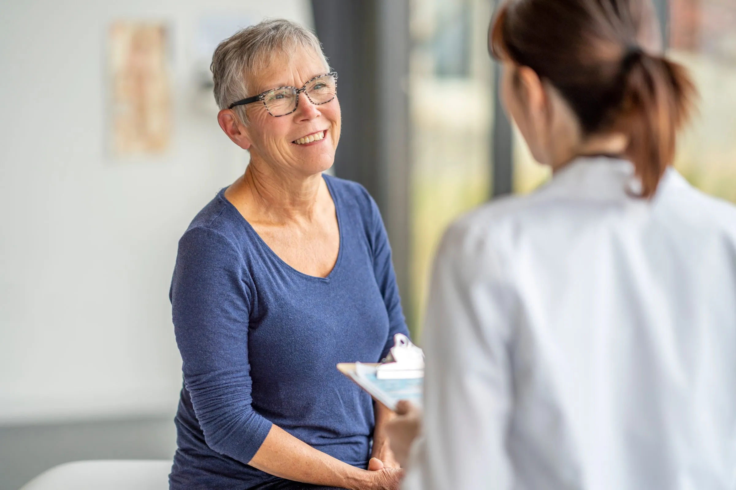 A smiling older woman talks with a doctor