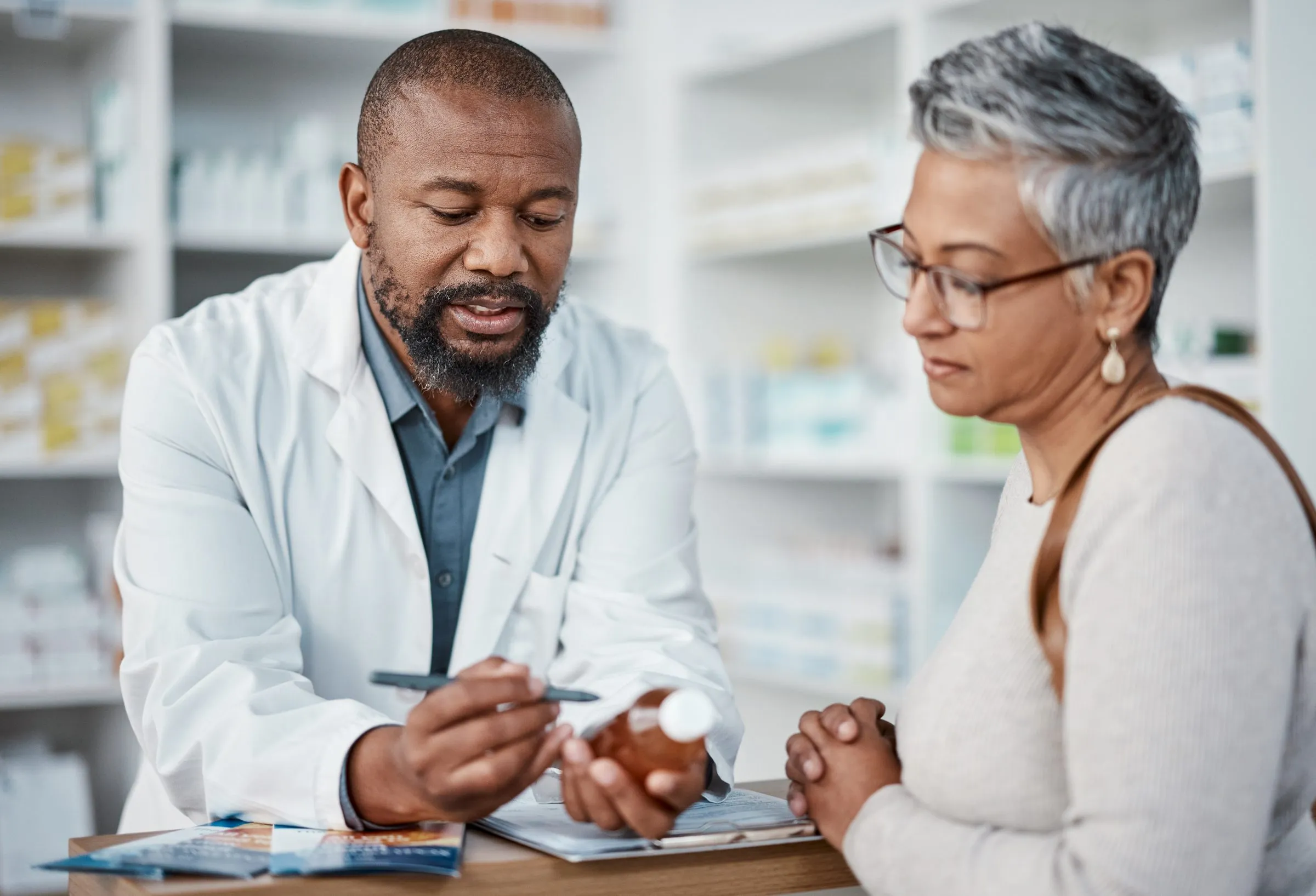 A pharmacist explains a prescription to a woman at the counter