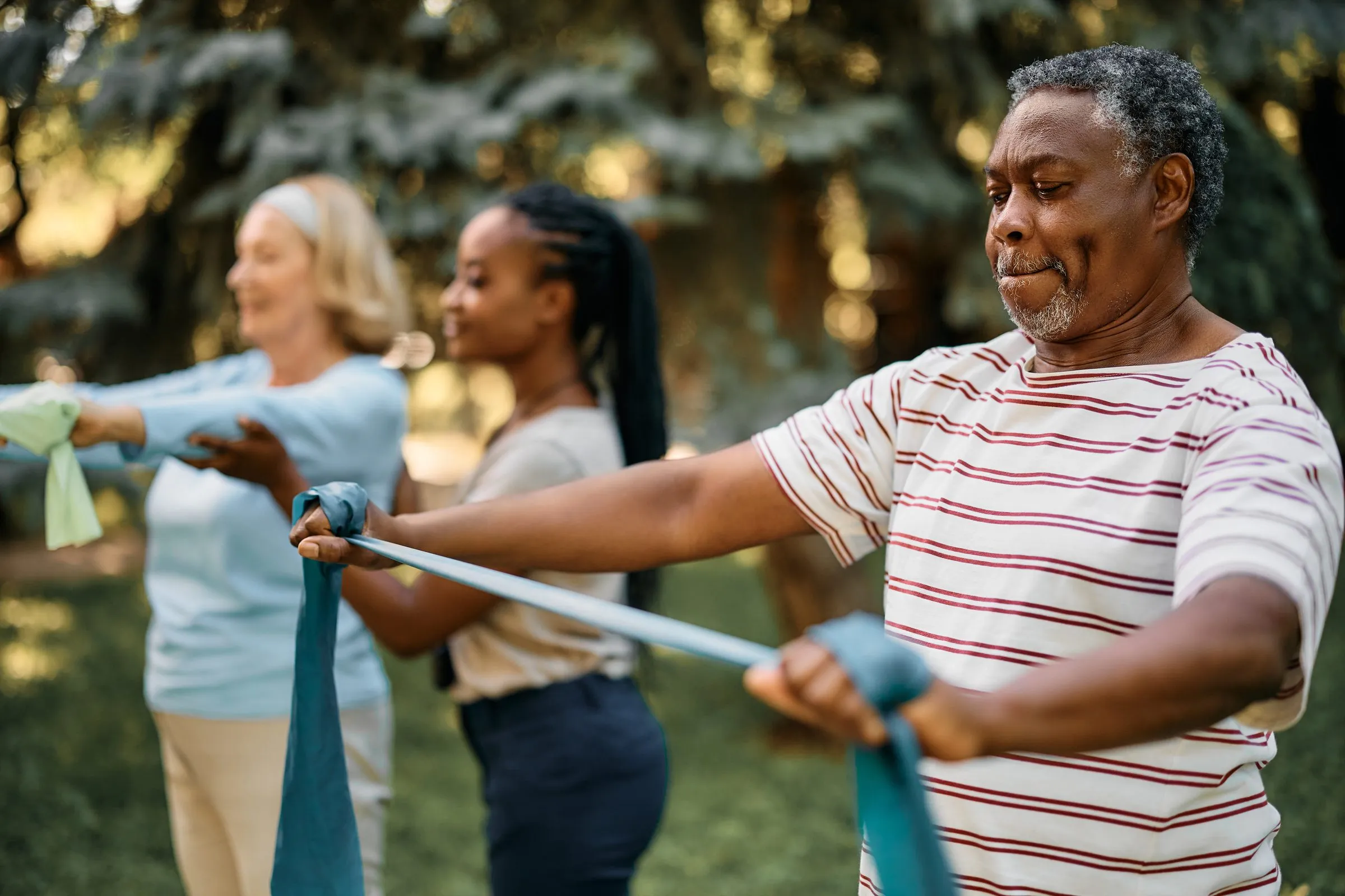 Older adults exercise with resistance bands in a park