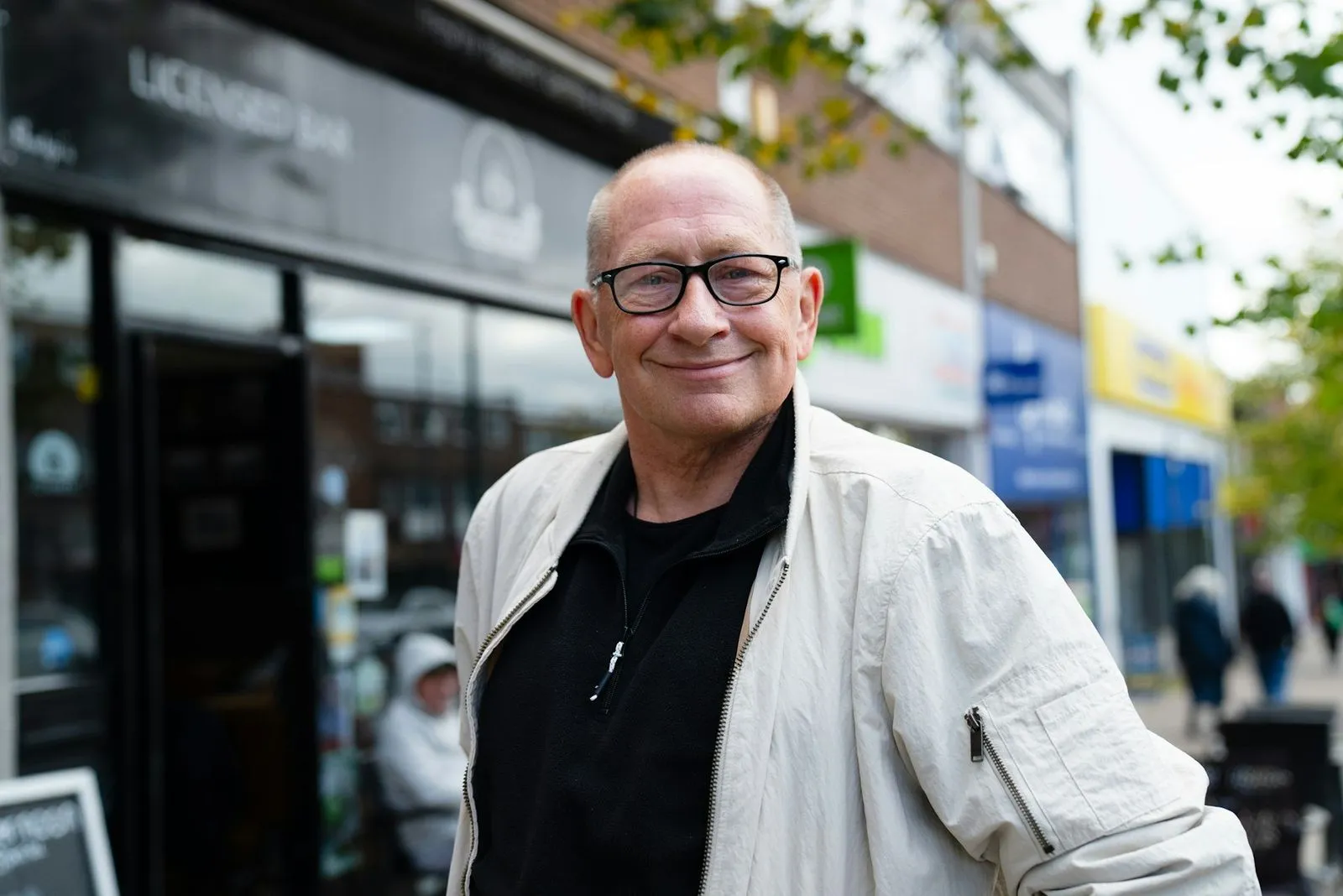 An older man smiles on his local high street