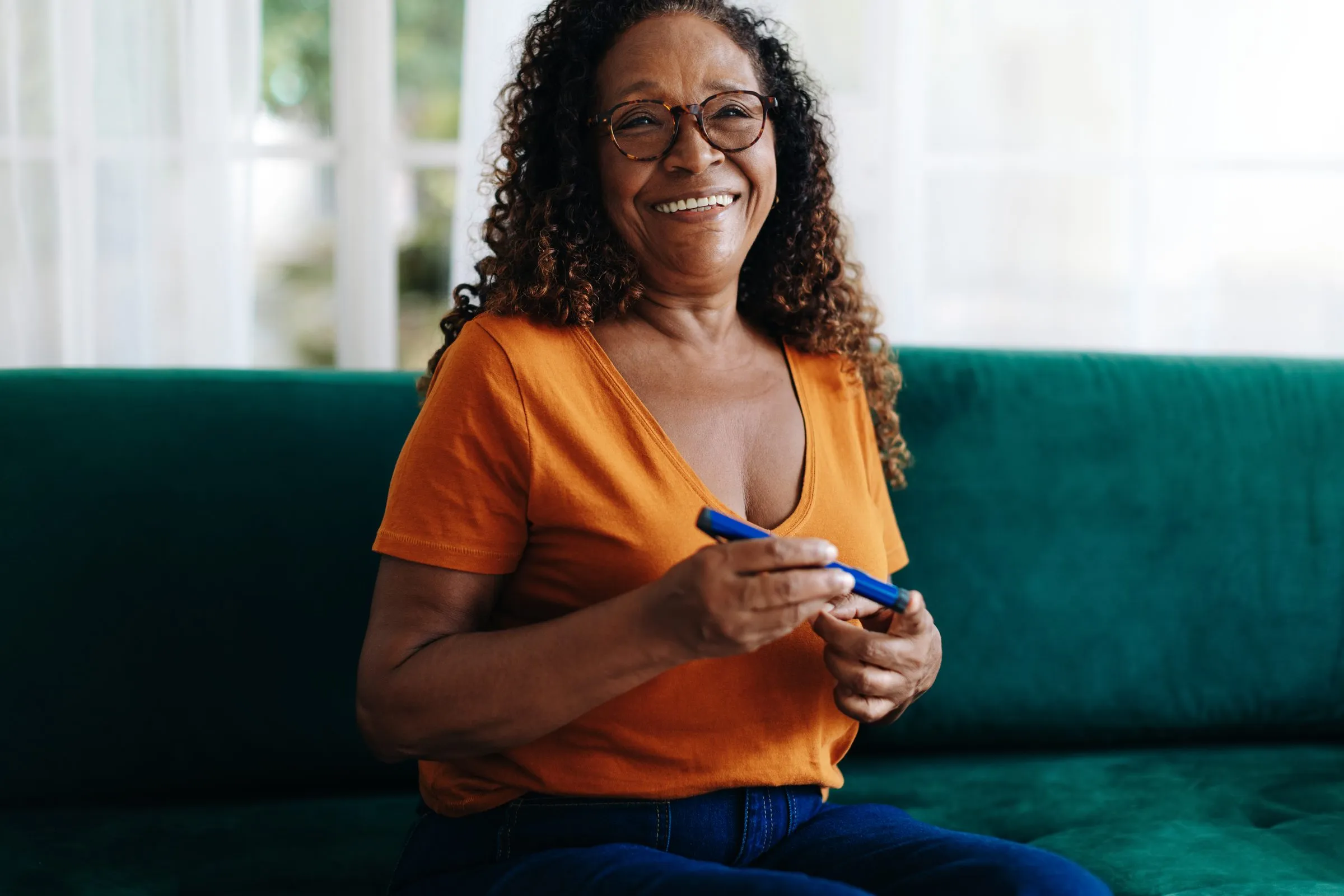 A smiling woman checks her blood sugar at home
