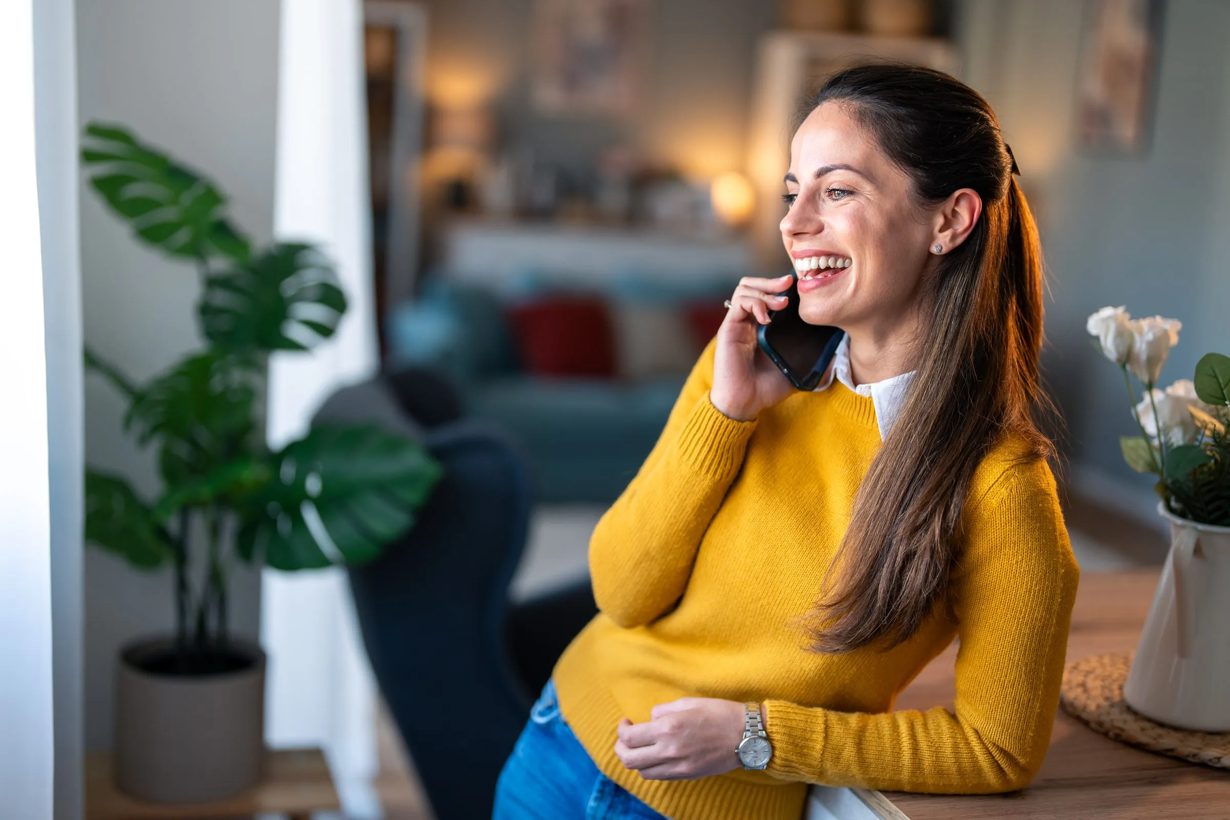 A woman laughs as she talks on the phone at home