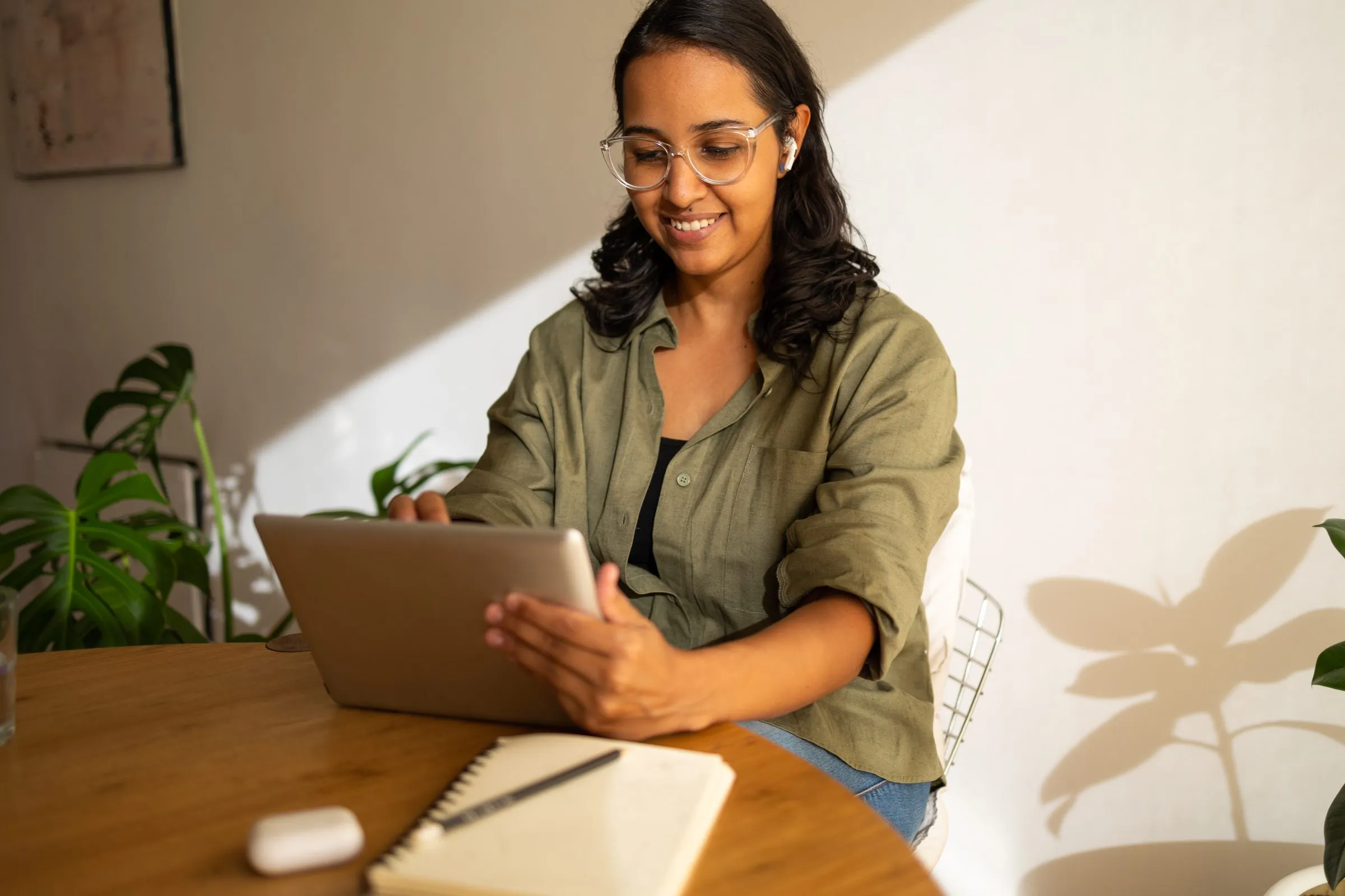 A woman uses a tablet at her table at home