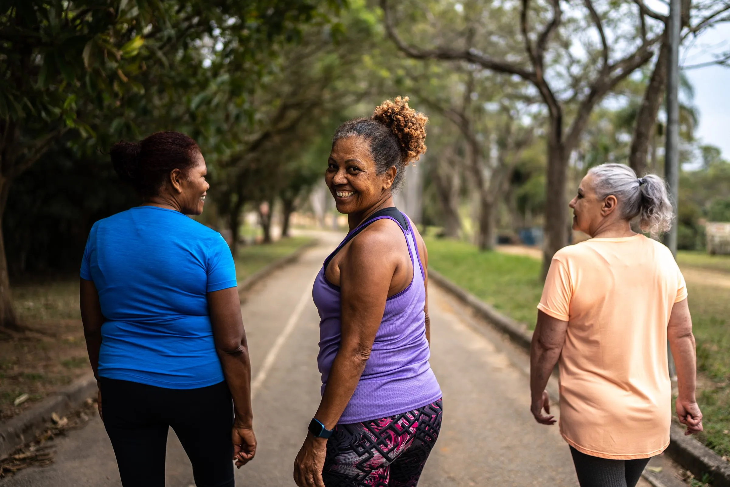 Three women talk as they walk along a path in a park
