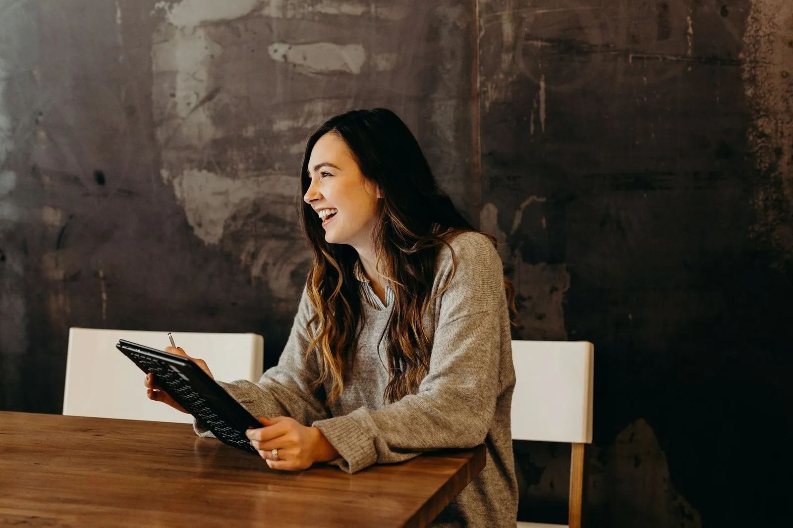 A woman uses a tablet at her kitchen table